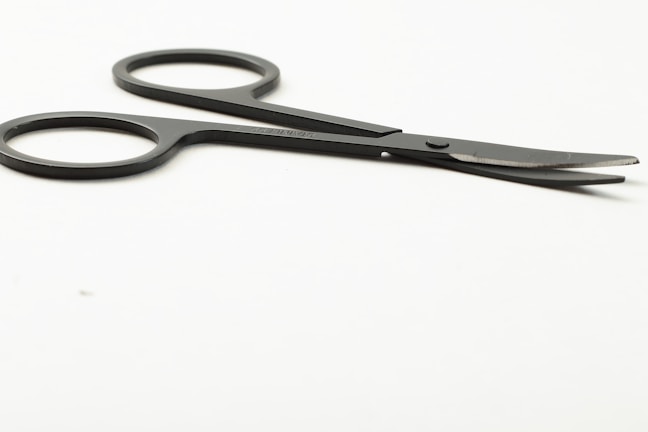 Close-up of a shiny stainless steel surgical scissors resting on a clean white surface.