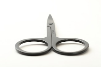 Sterile surgical scissors with metallic grey accents displayed on a clinical white backdrop.