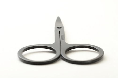 Close-up of a stainless steel surgical scissors reflecting light against a clean white background.