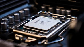 A close-up view of a computer processor installed on a motherboard, showing intricate details of the CPU socket and surrounding electronic components. The processor is labeled with technical specifications, emphasizing the precision and complexity of computer hardware design.