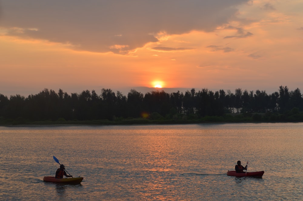 silhouette of 2 people riding on boat during sunset