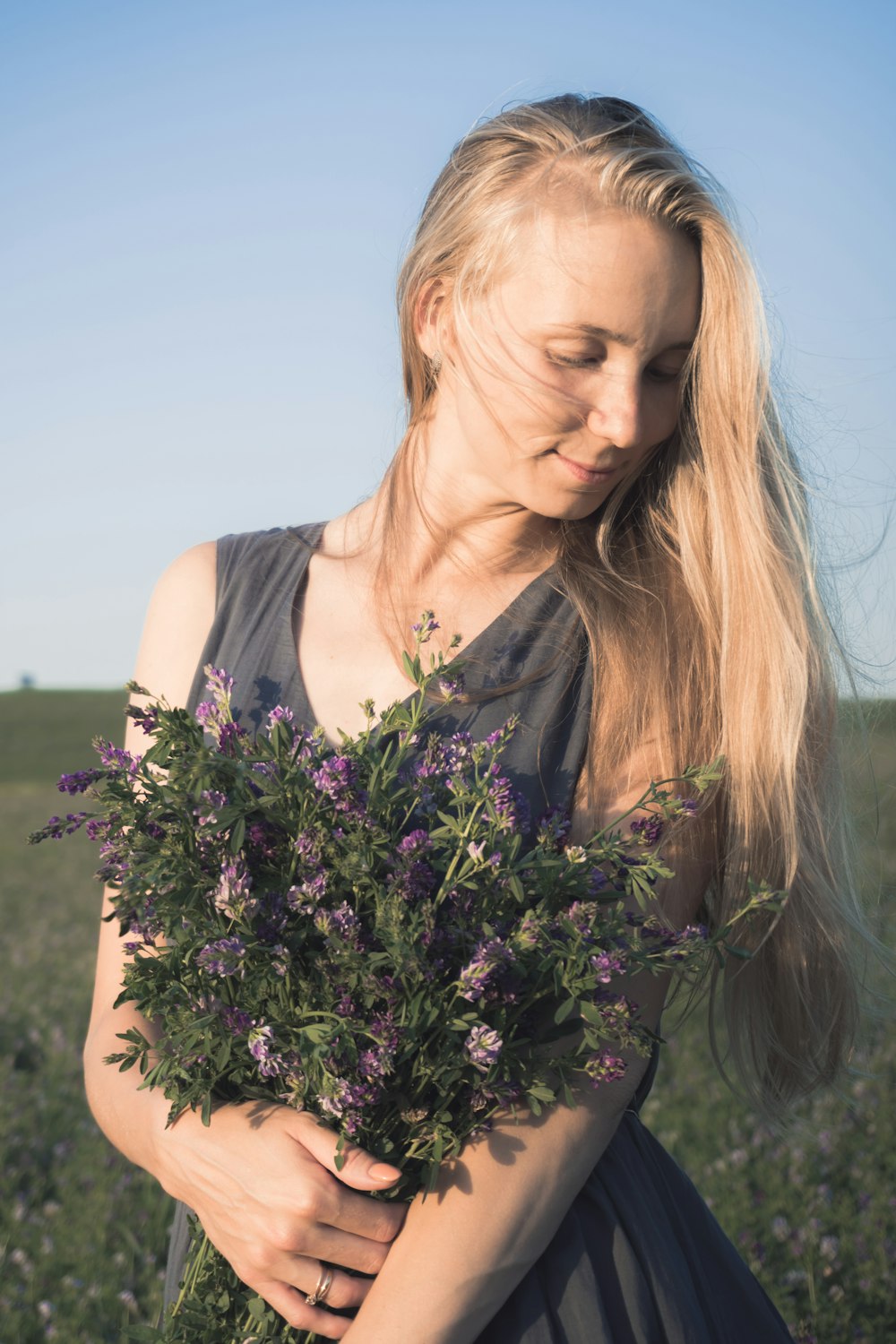 woman in white tank top holding purple flowers