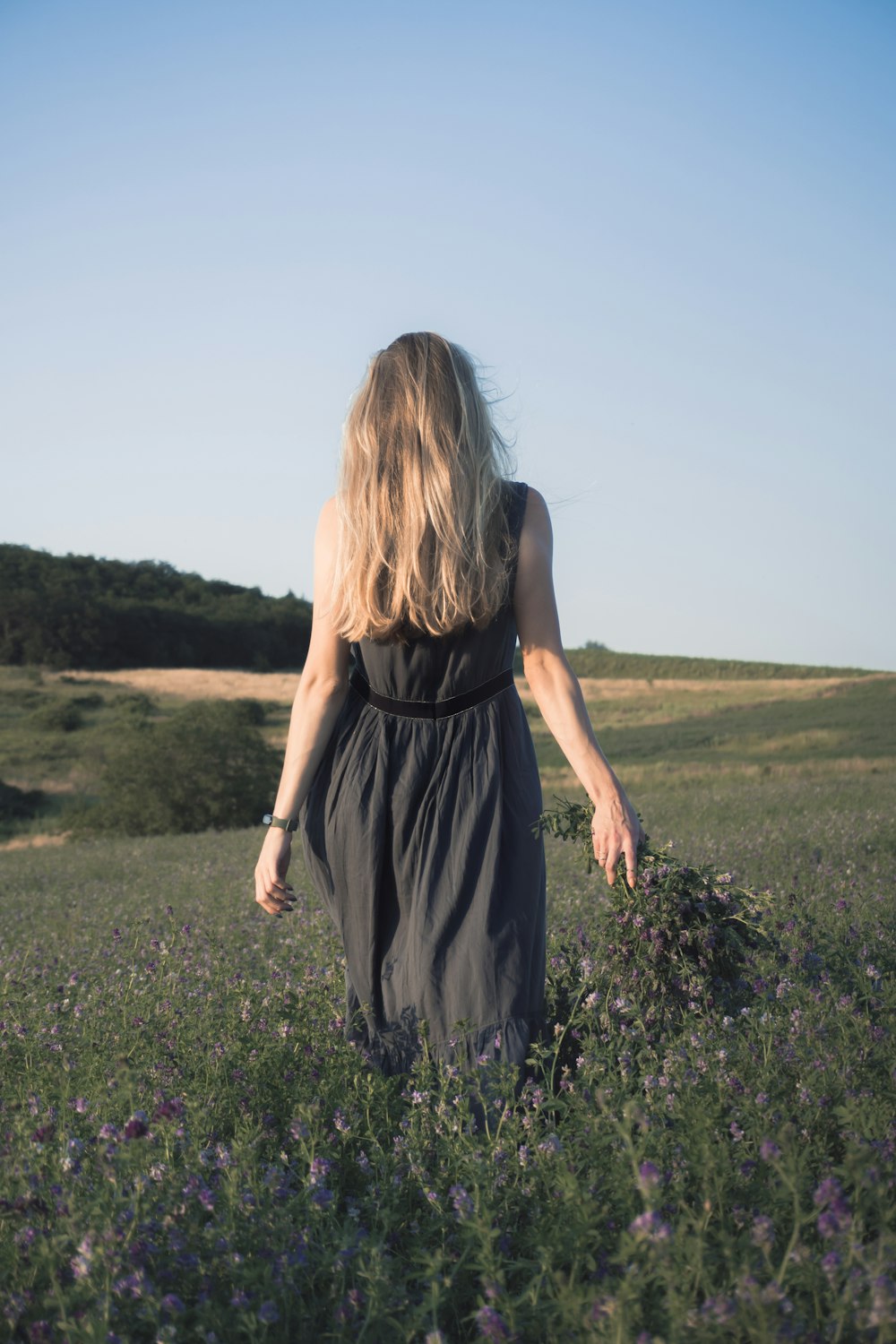 woman in black sleeveless dress standing on green grass field during daytime