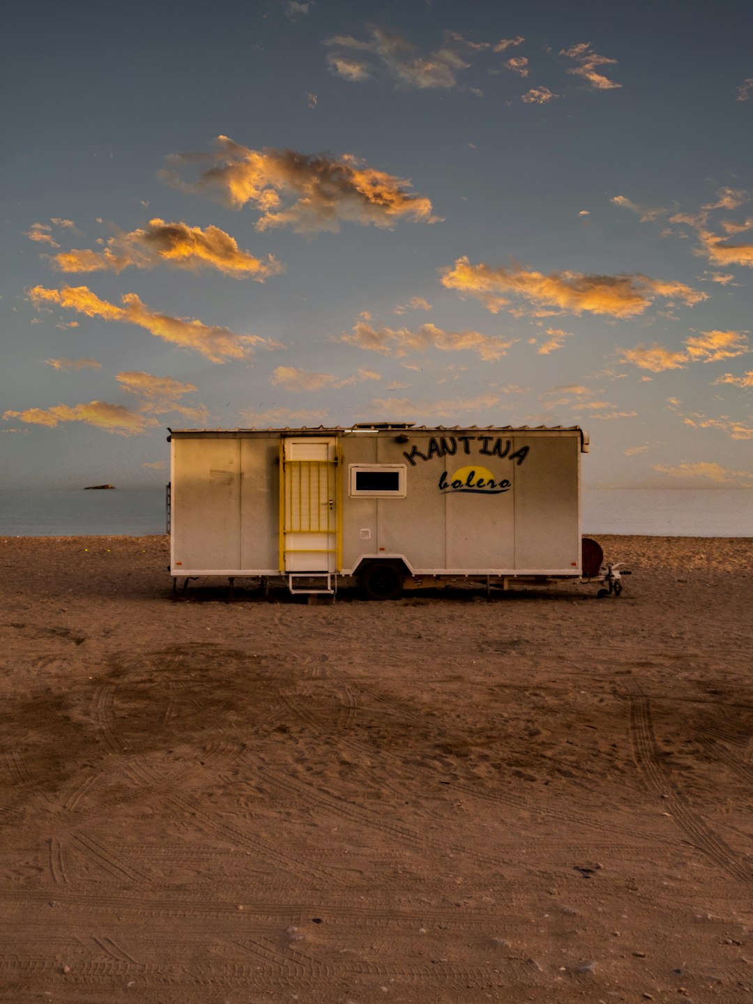 white and red camper trailer on beach during sunset