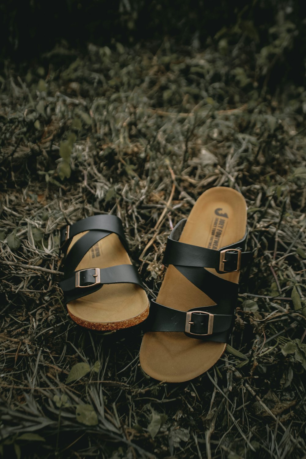 brown and black leather sandals on green grass