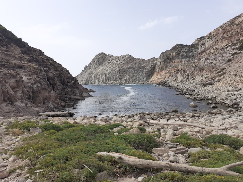 Montaña rocosa al lado del cuerpo de agua durante el día