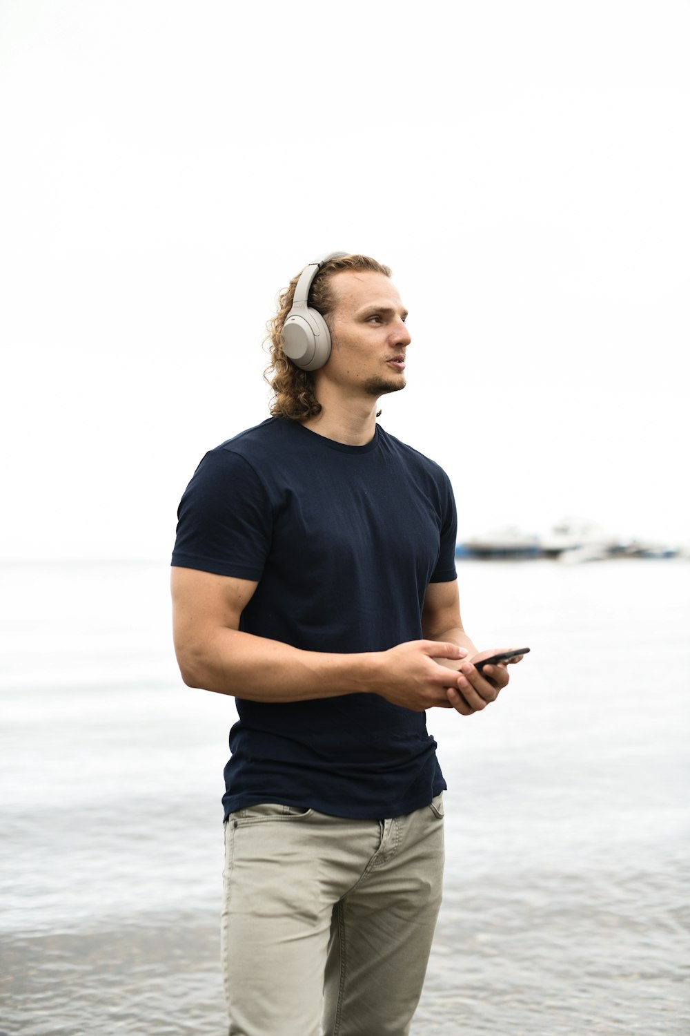 man in blue crew neck t-shirt and gray denim shorts holding smartphone