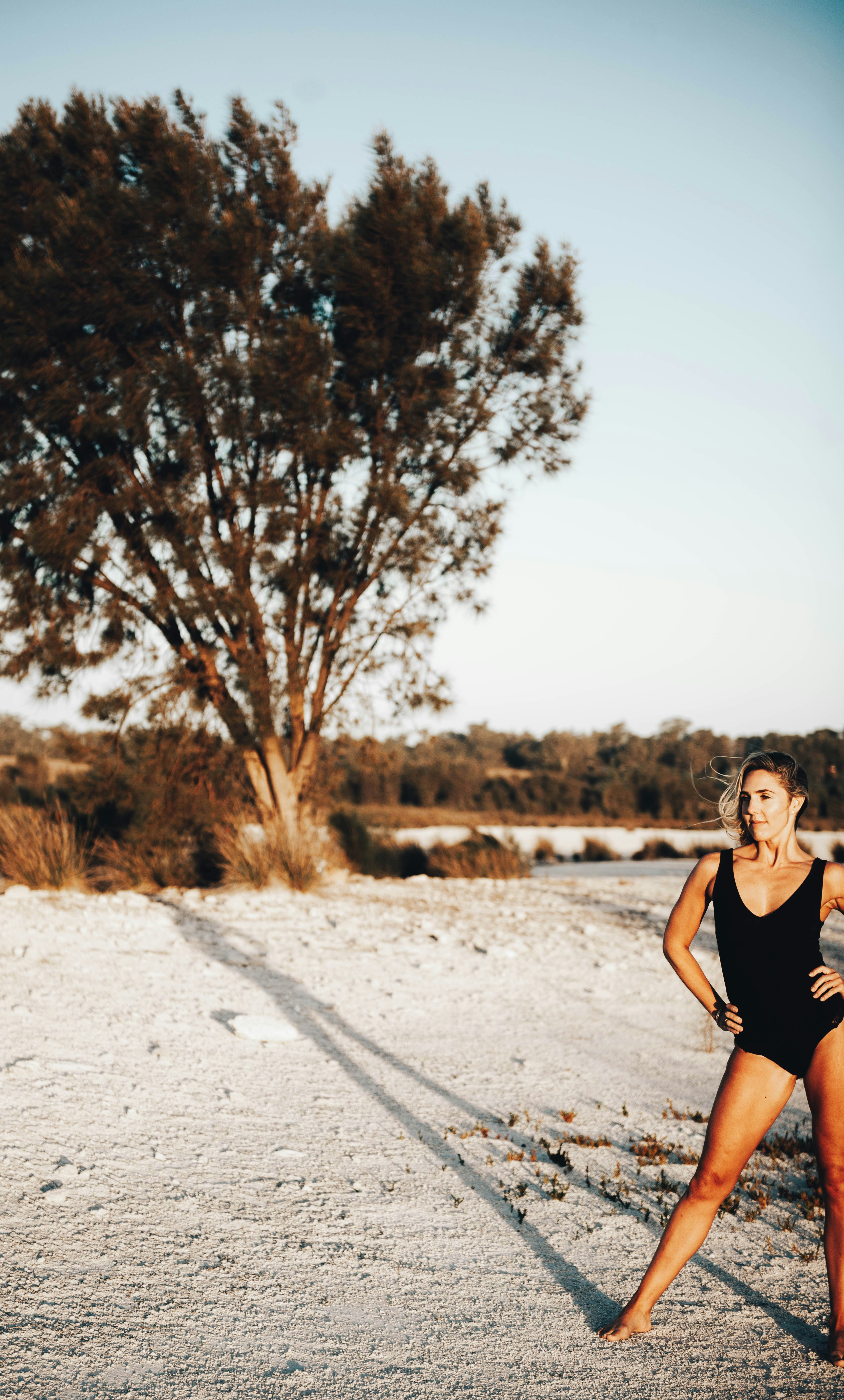 woman in black tank top standing on white sand during daytime
