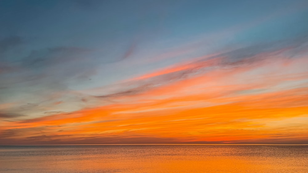 body of water under orange and blue sky