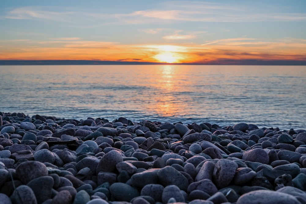 rochas cinzentas na costa do mar durante o pôr do sol