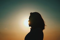 a silhouette of a person with the sun in the background