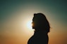 a silhouette of a person with the sun in the background