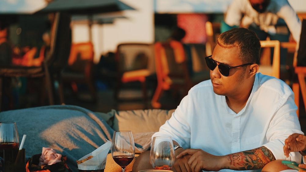 homme en t-shirt blanc à col rond portant des lunettes de soleil noires  tenant un verre à boire clair photo – Image Indonésie gratuite sur Unsplash