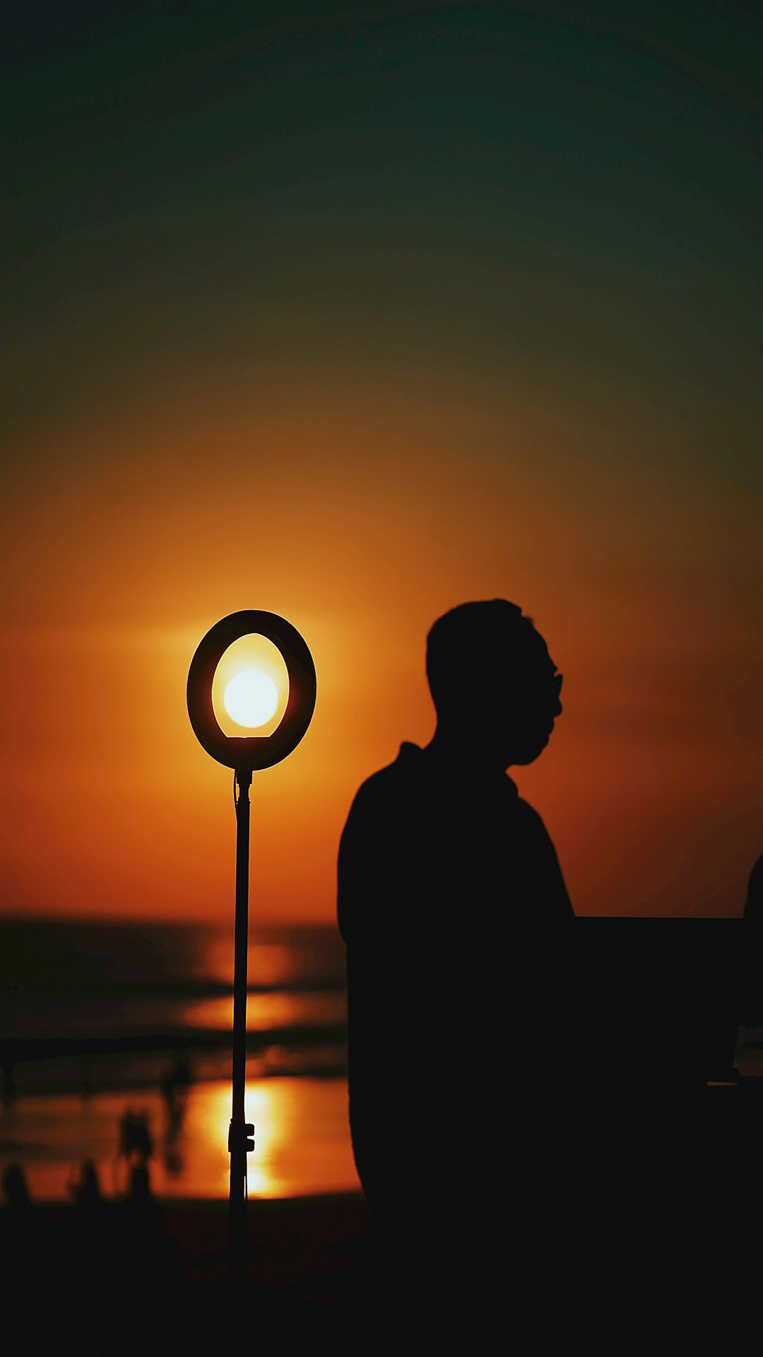 silhouette of man standing near lamp post during sunset