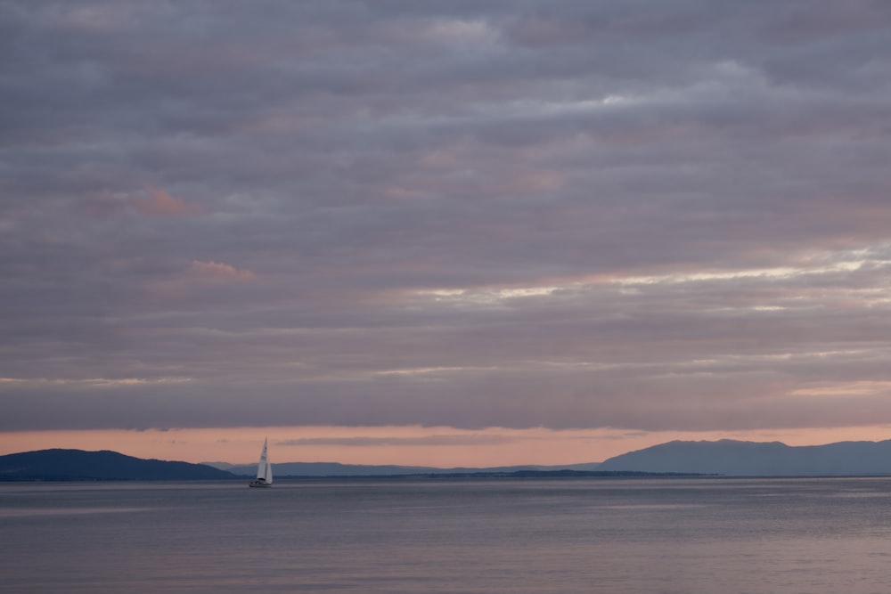 white sailboat on sea under cloudy sky during daytime