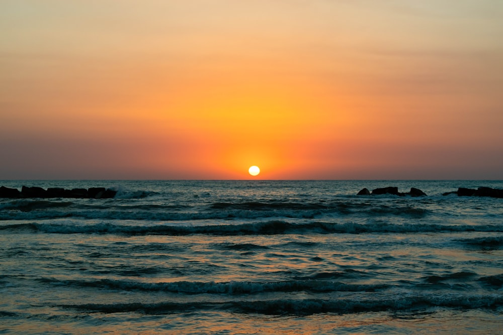 sea waves crashing on shore during sunset