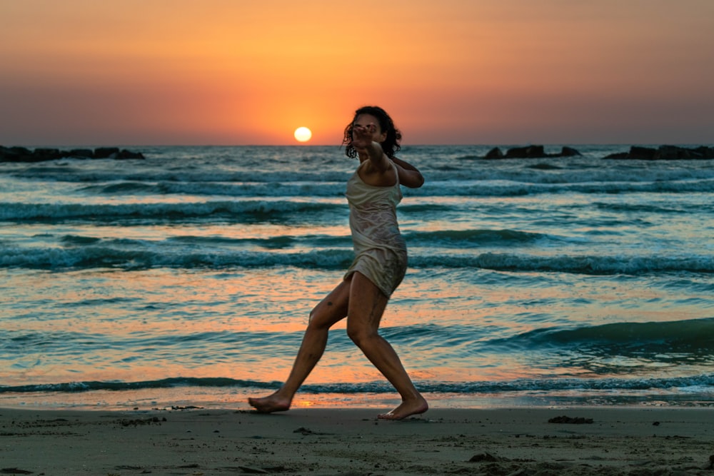 woman in white dress standing on beach during sunset
