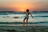 Sunset beach party with dancers moving freely under warm orange skies and rhythmic music.