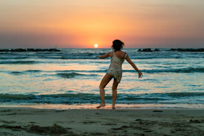Sunset beach party with dancers moving freely under warm orange skies and rhythmic music.