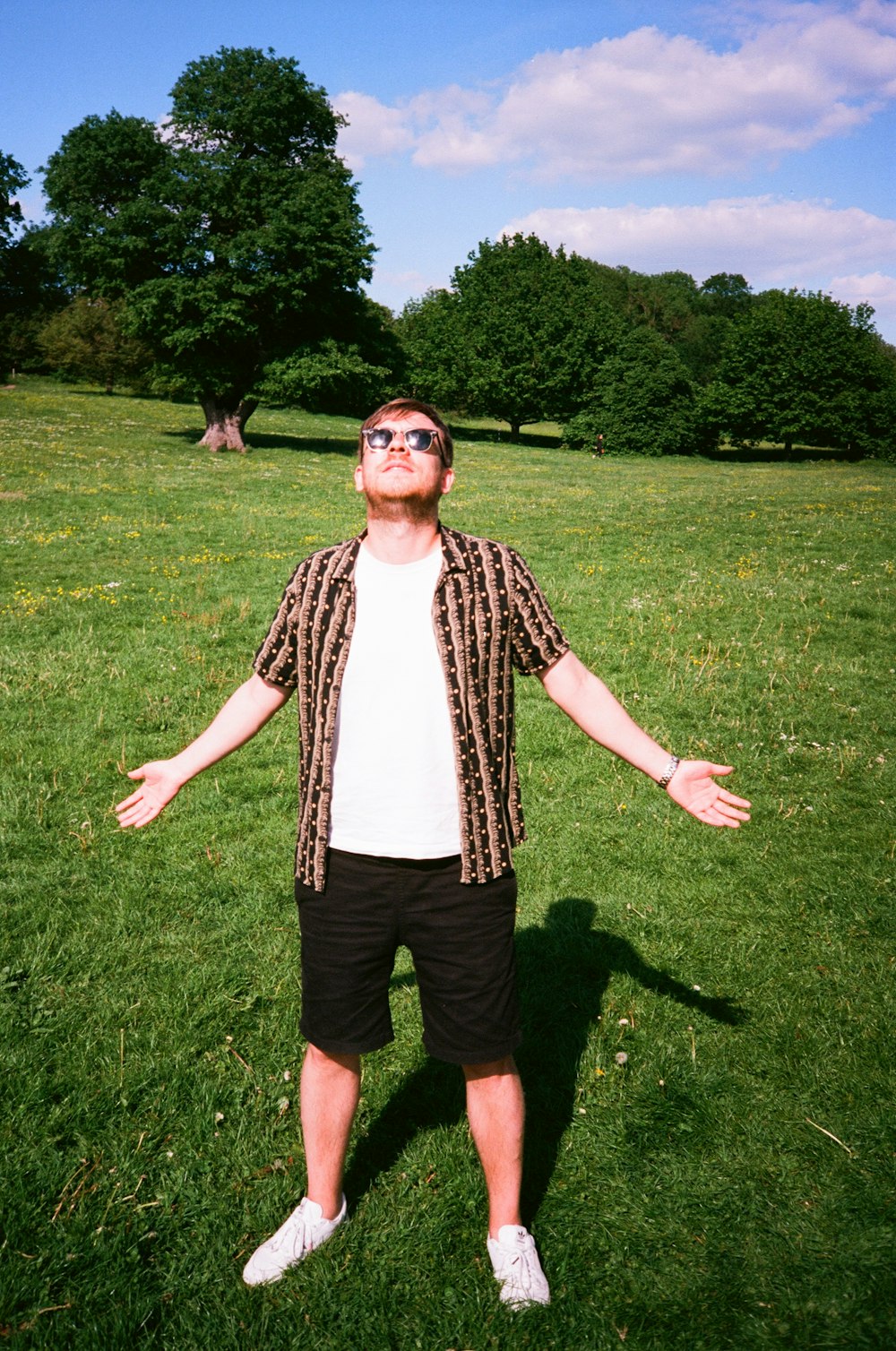 man in black and white checkered button up shirt standing on green grass field during daytime