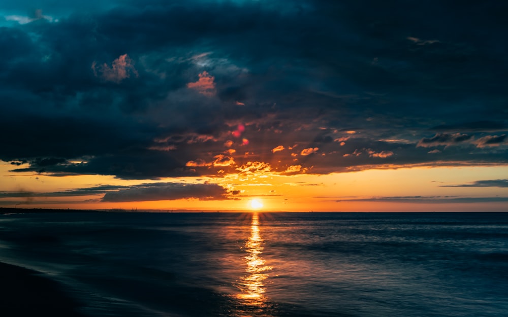 body of water under cloudy sky during sunset