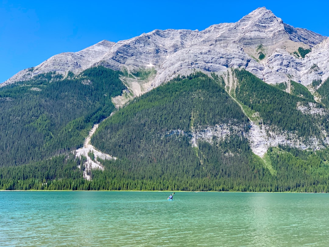 person riding on boat on lake near mountain during daytime