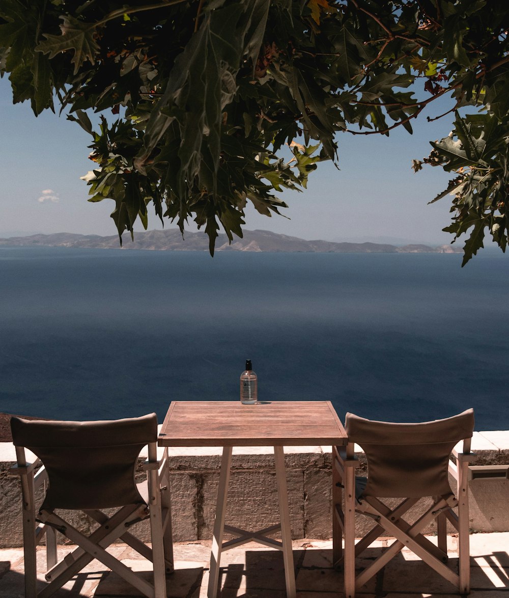 Table et chaises en bois brun près de la mer pendant la journée