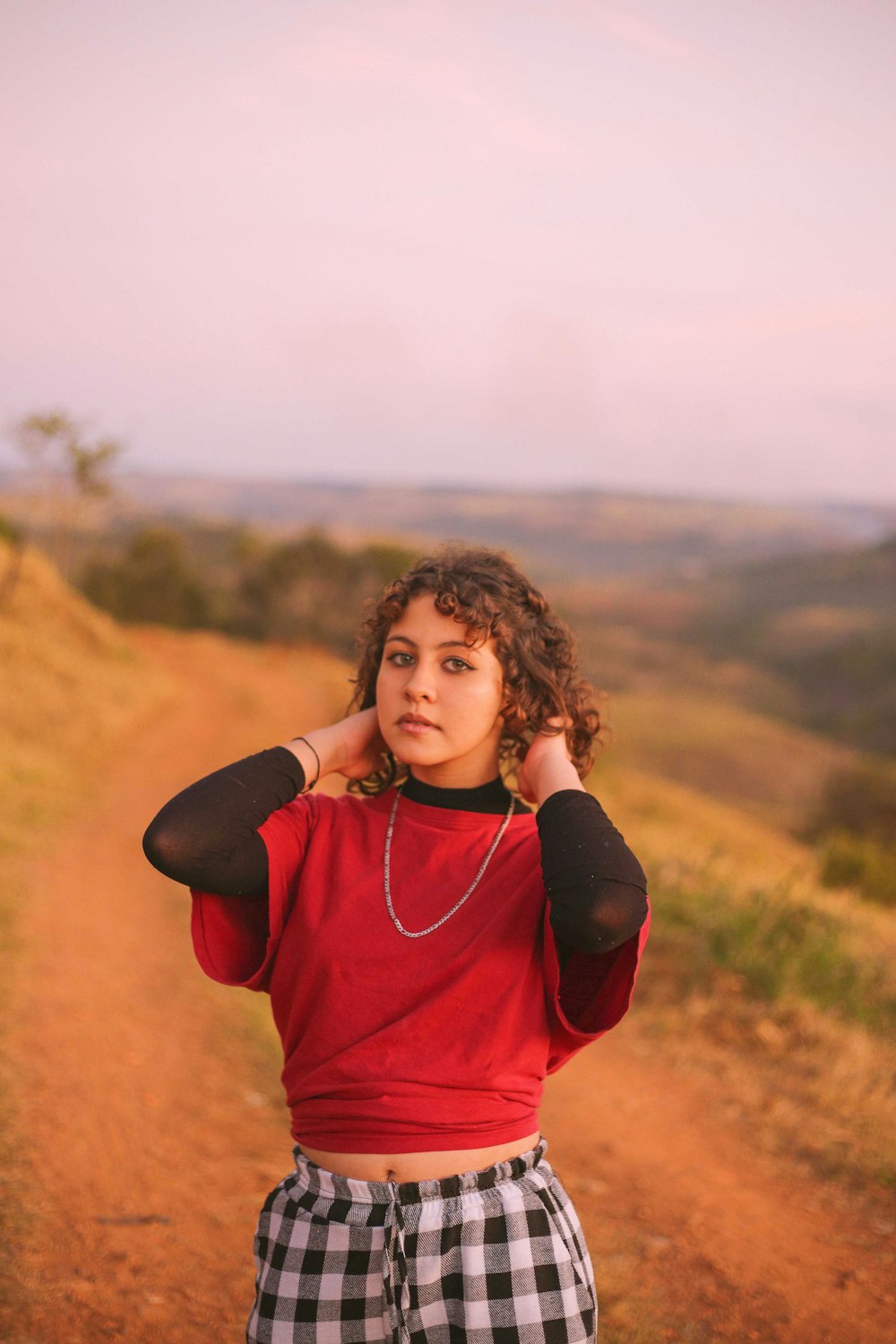 woman in red long sleeve shirt standing on brown field during daytime