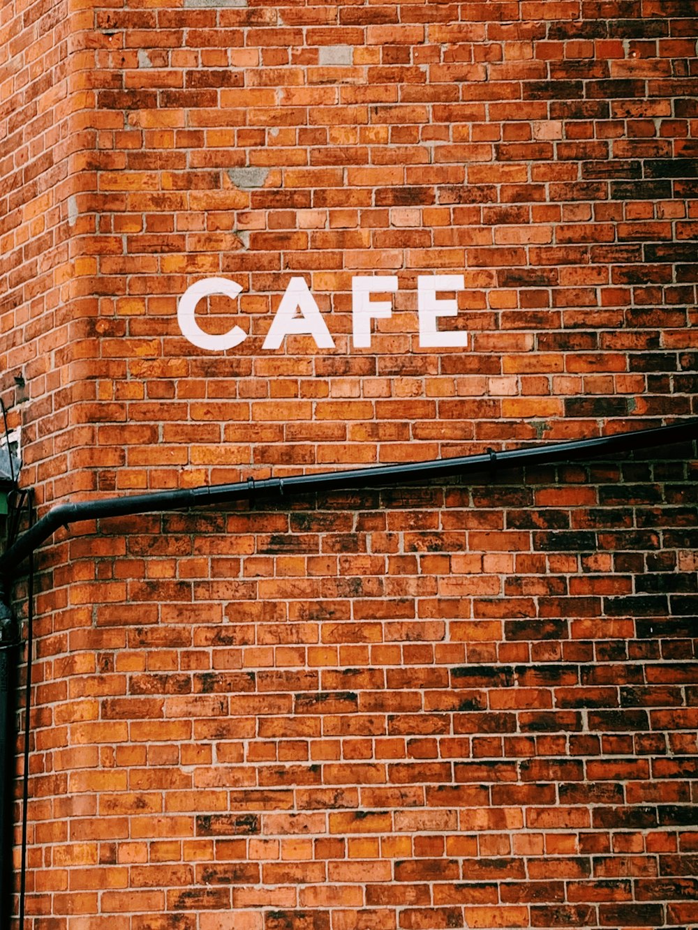un mur de briques avec un panneau qui dit café dessus