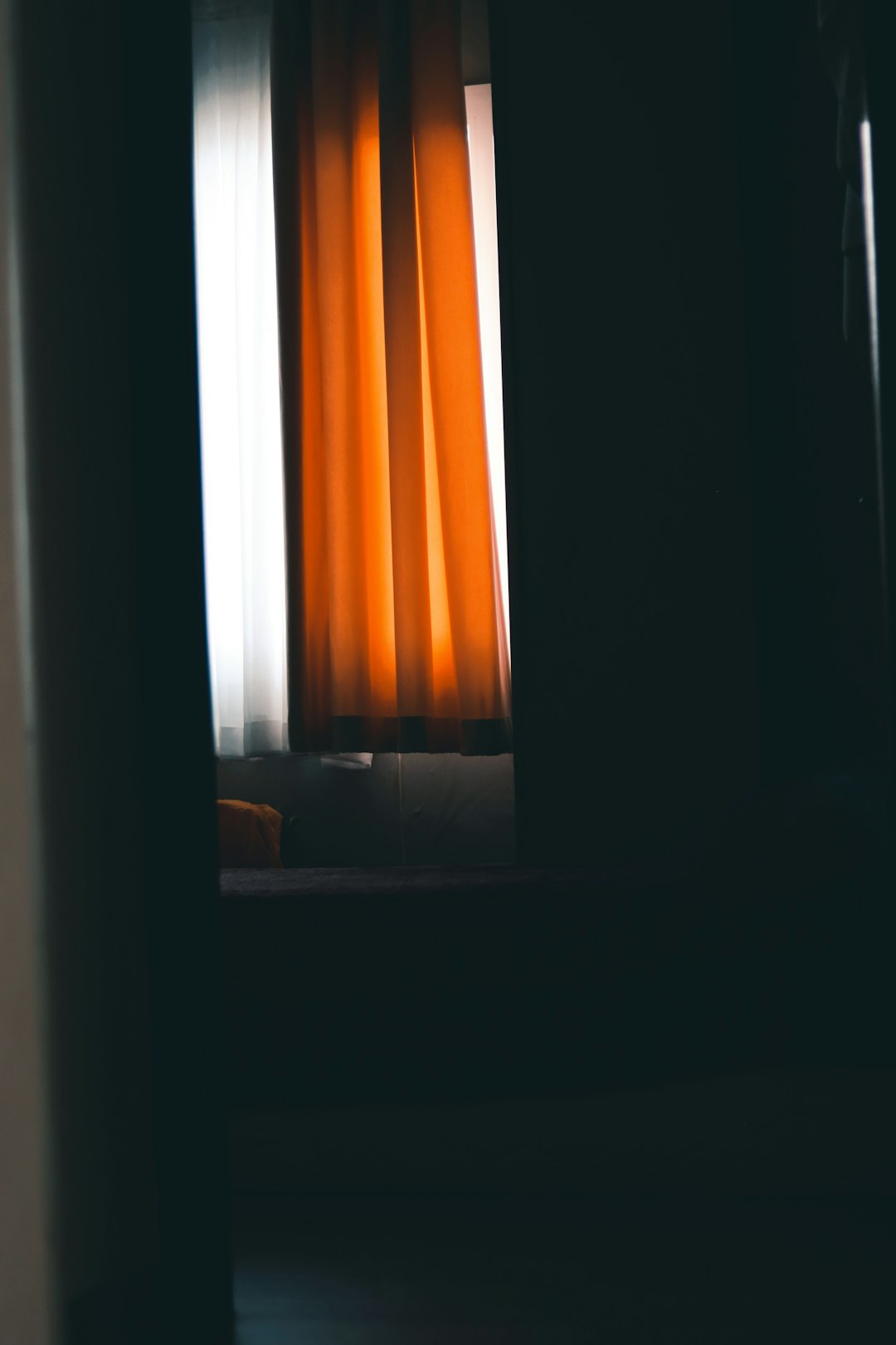 black framed glass window with orange curtain