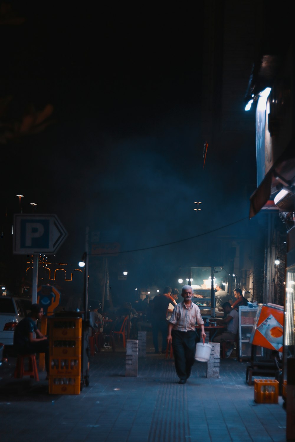 man in white shirt standing on street during nighttime