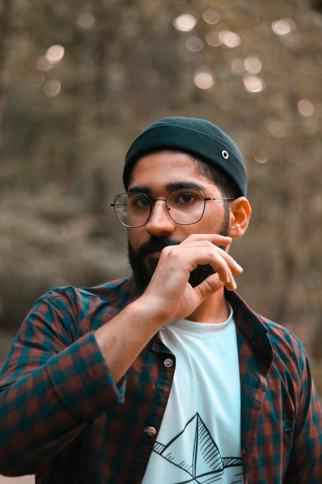 man in blue and red plaid button up shirt wearing black framed eyeglasses and white cap