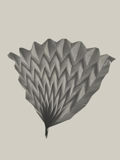 A detailed origami structure with multiple folds creating a symmetrical and fan-like pattern. The paper appears textured and is arranged in a visually appealing manner.