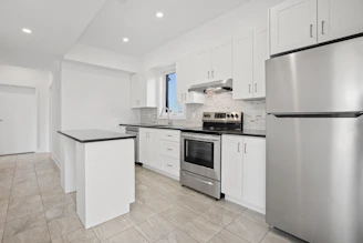 Bright modern kitchen featuring glossy white tiles and new cabinetry.
