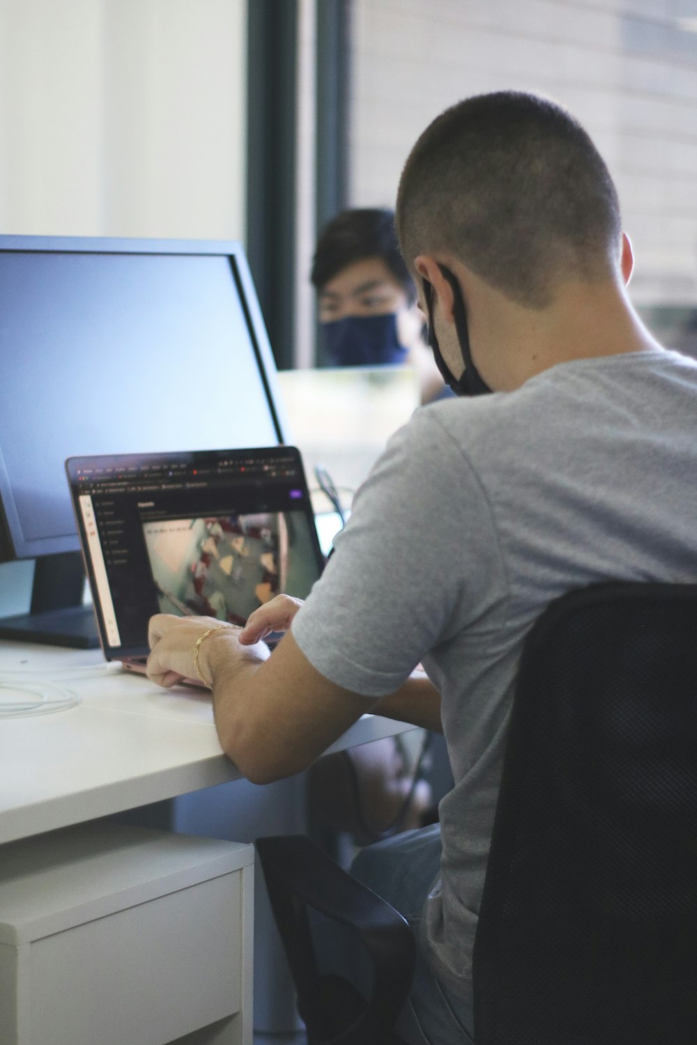 man in gray t-shirt sitting on chair in front of computer monitor