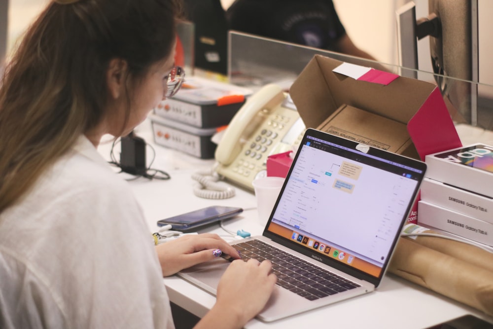 woman in white shirt using macbook pro