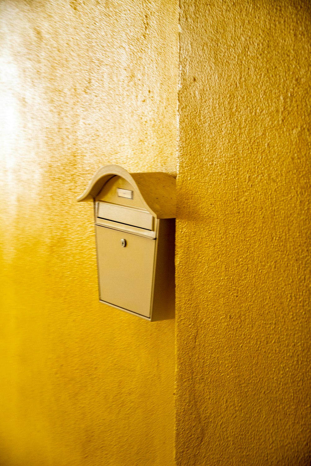 gray steel trash bin beside yellow painted wall