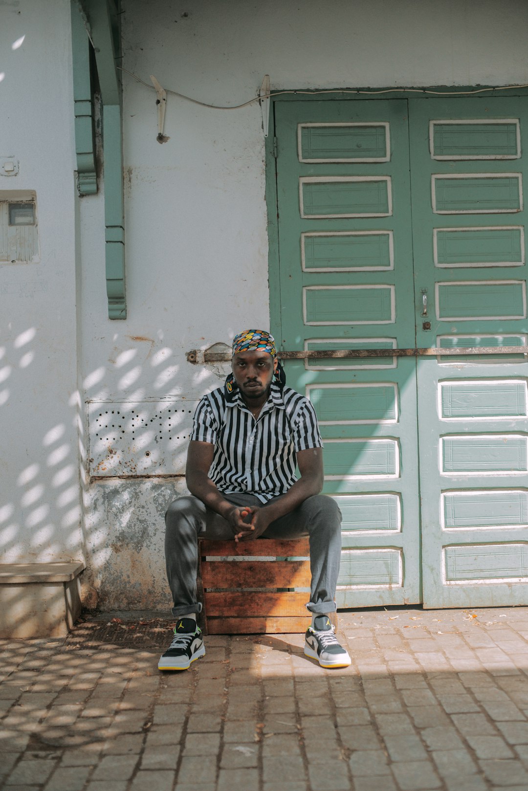 man in black and white stripe shirt sitting on brown wooden bench