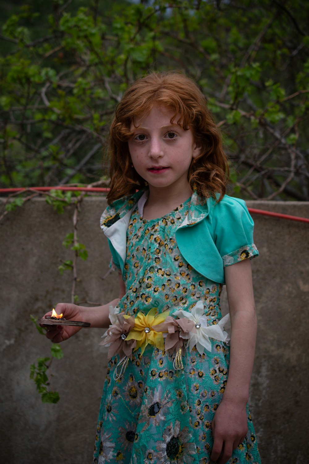 girl in white and green floral dress holding brown cup