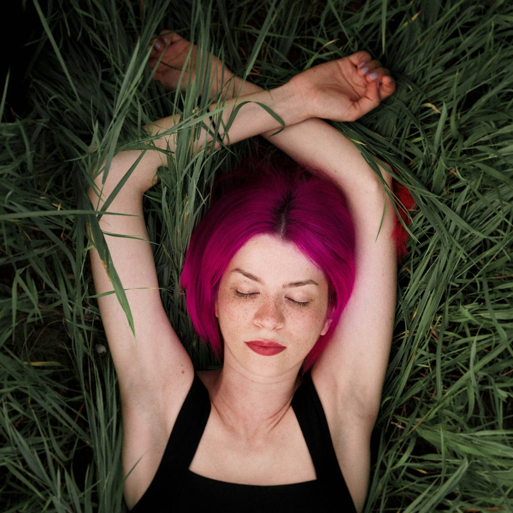 woman in black tank top lying on green grass