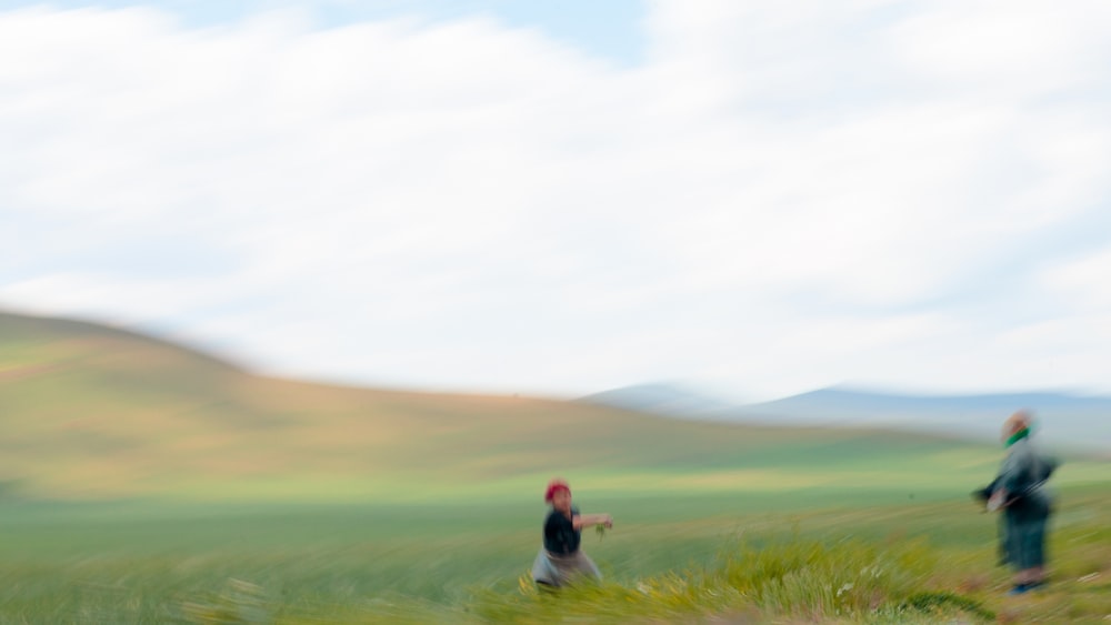 man in black jacket sitting on green grass field during daytime