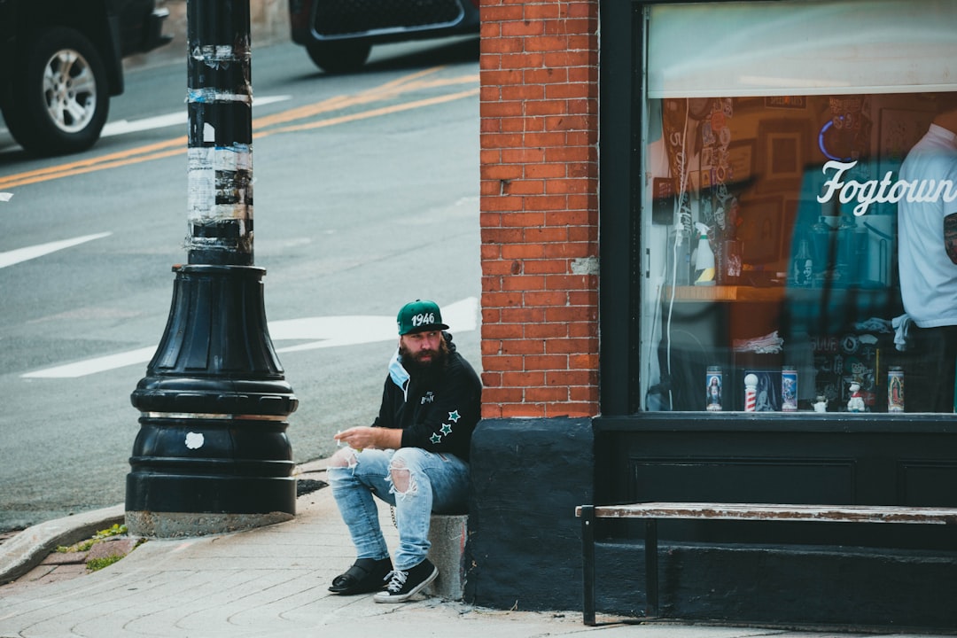 man in blue denim jacket and blue denim jeans sitting on black bench