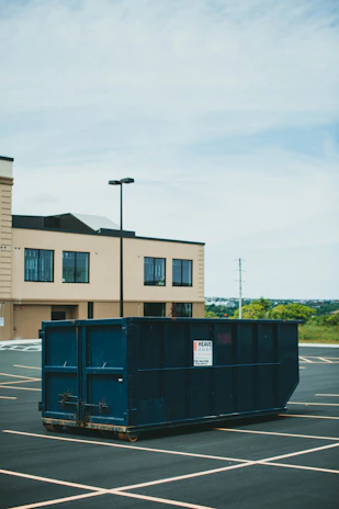 blue trash bin beside brown concrete building during daytime