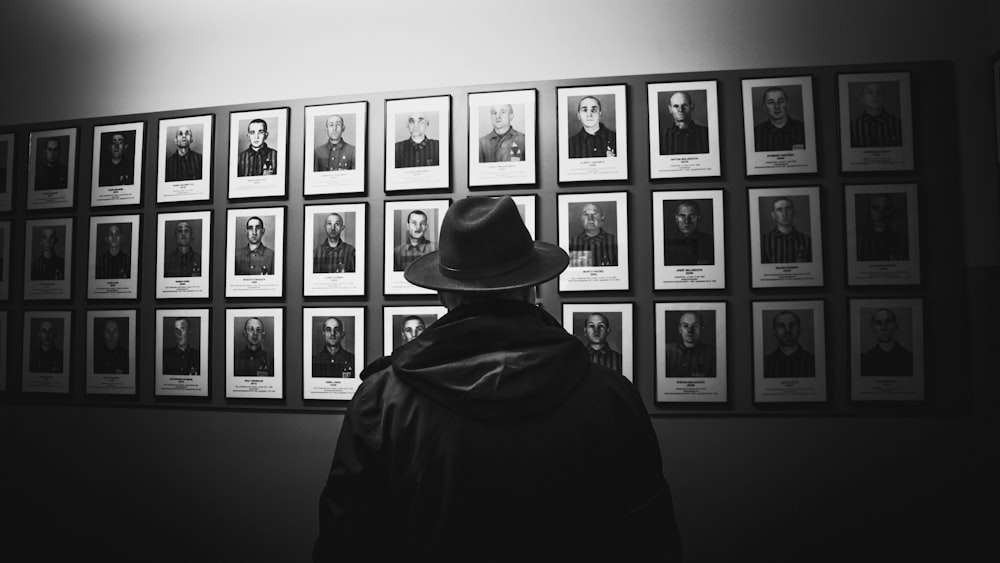 foto em tons de cinza do homem no capuz preto e chapéu preto
