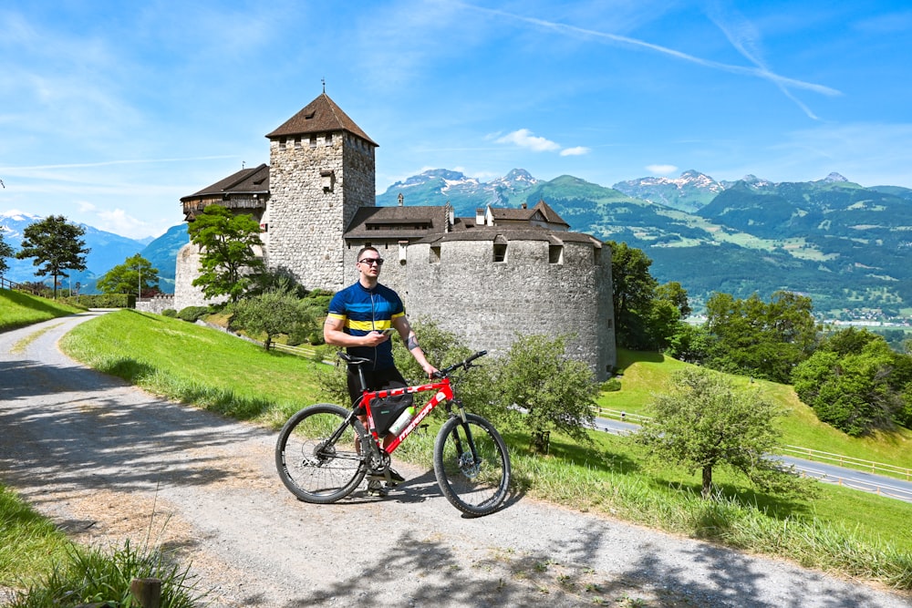 Mann im blauen Hemd fährt tagsüber auf einem roten Fahrrad in der Nähe des braunen Betongebäudes