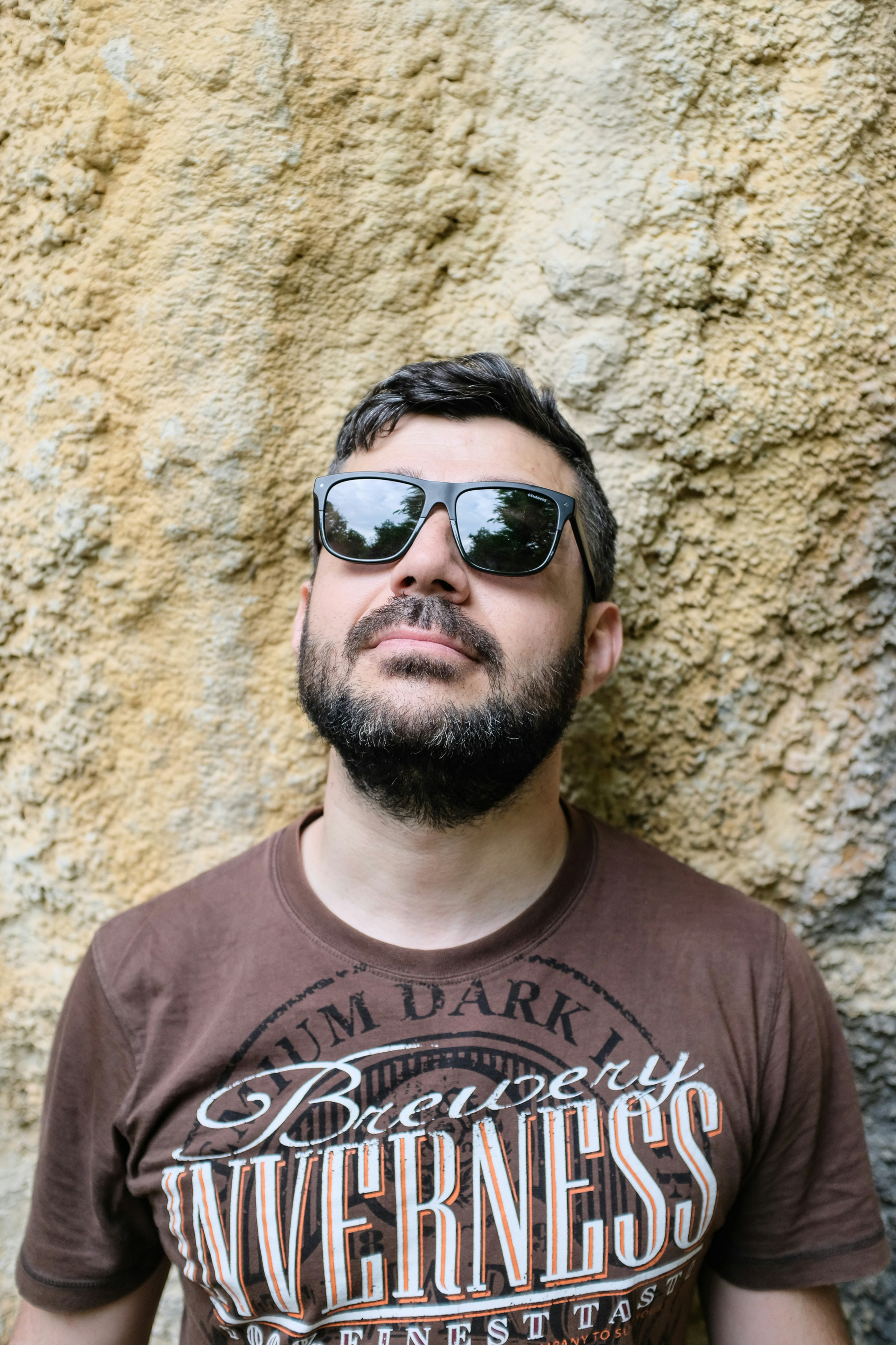 Mann im braunen Hemd mit Rundhalsausschnitt und schwarzer Sonnenbrille