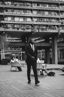 man in black suit standing on sidewalk