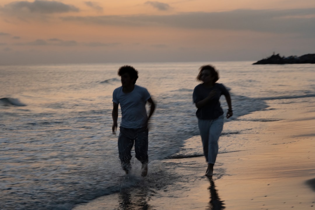 2 women and man standing on beach during sunset