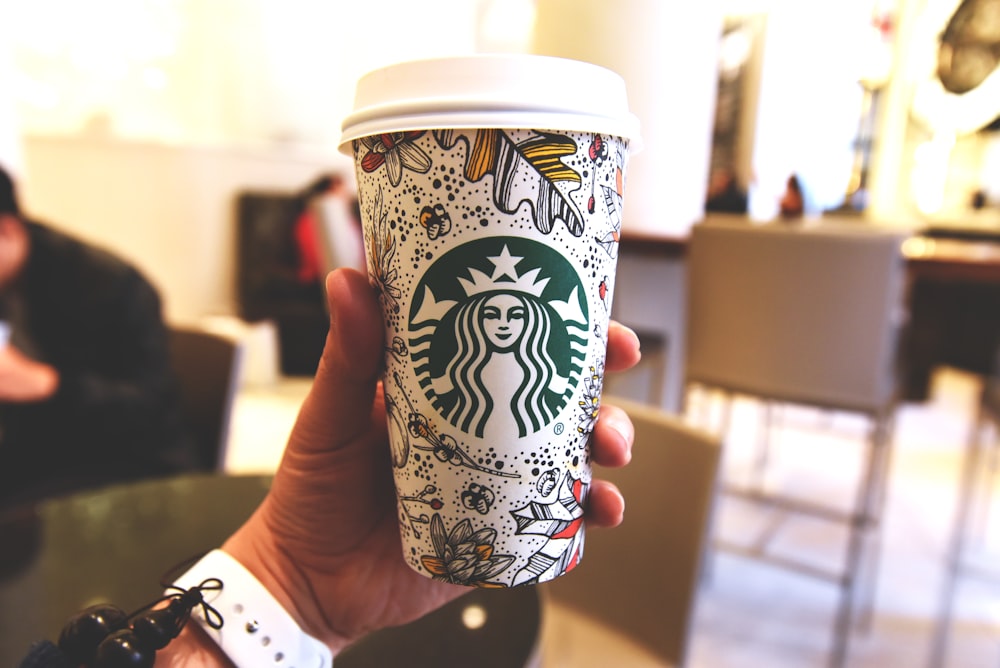 person holding white and brown disposable cup