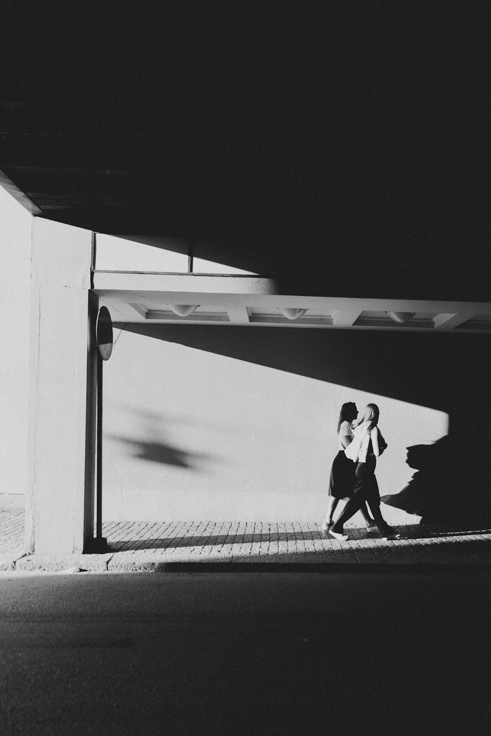 grayscale photo of man in black jacket and pants walking on pathway